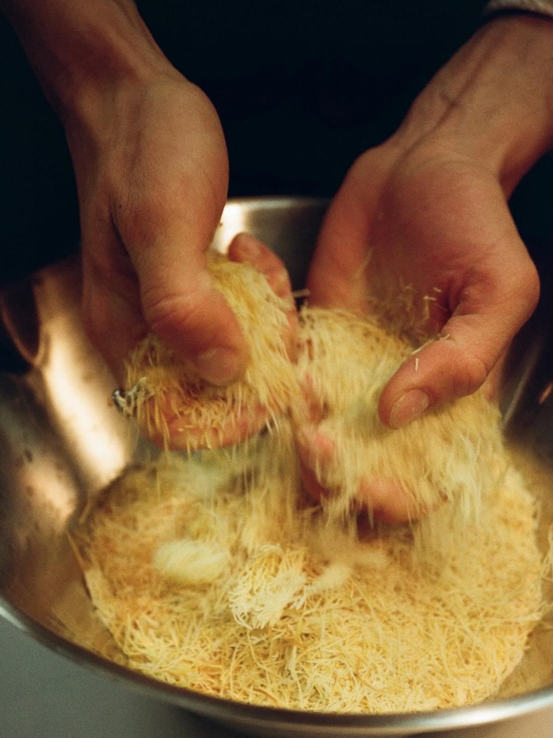Hands working pastry in a steel bowl