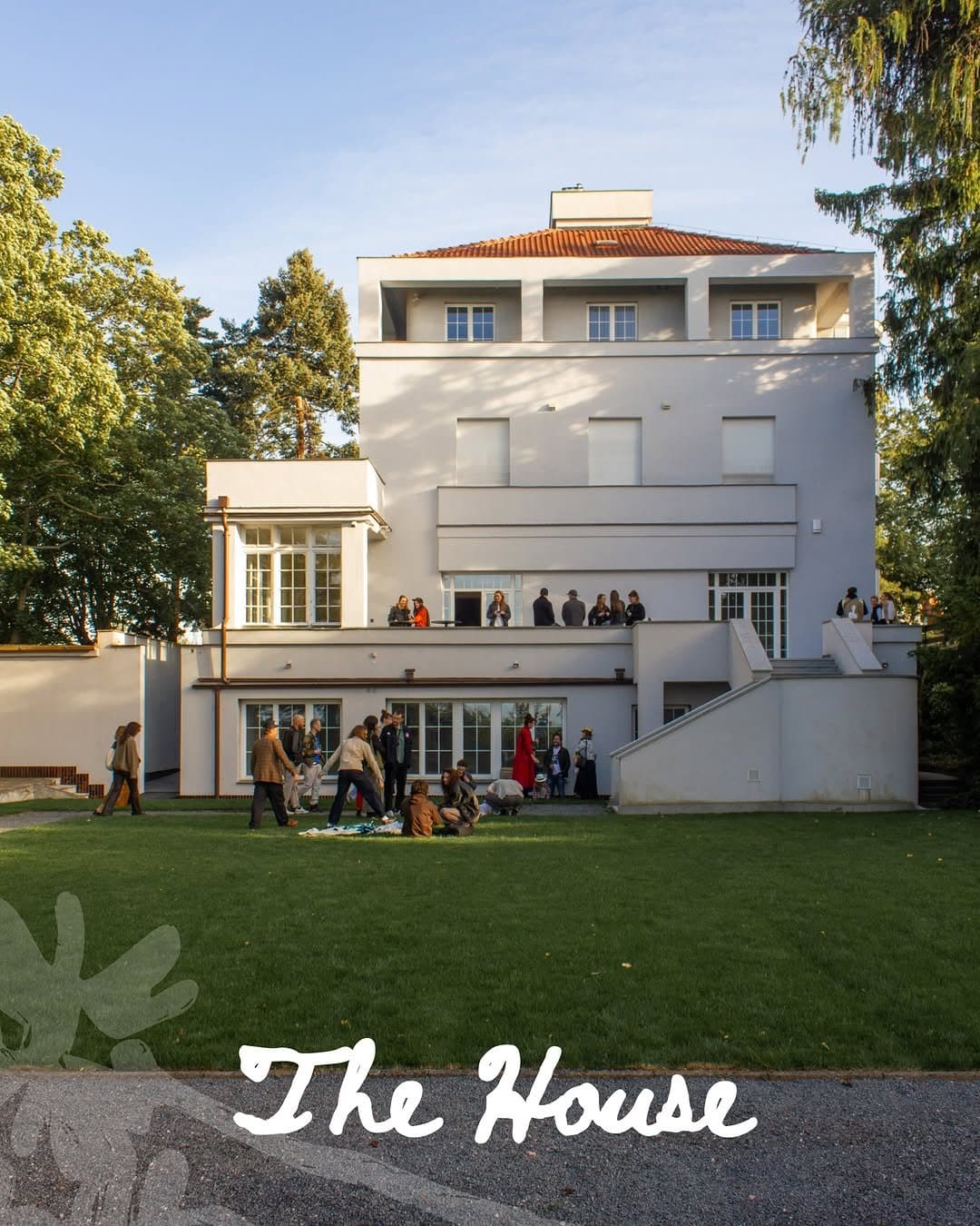 The House, a white modernist villa, with guests on the lawn